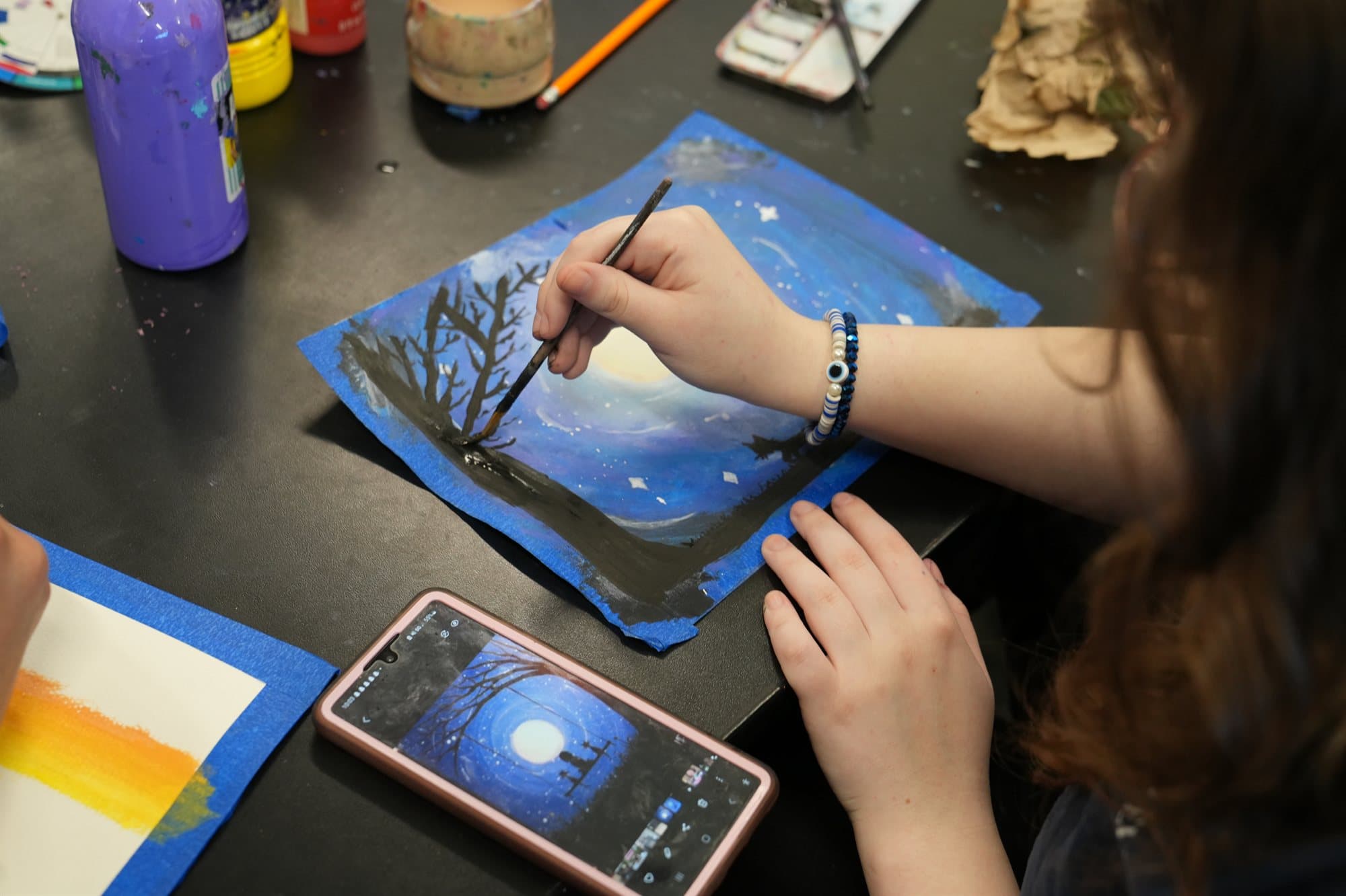 A Highland Prep art student painting a night landscape