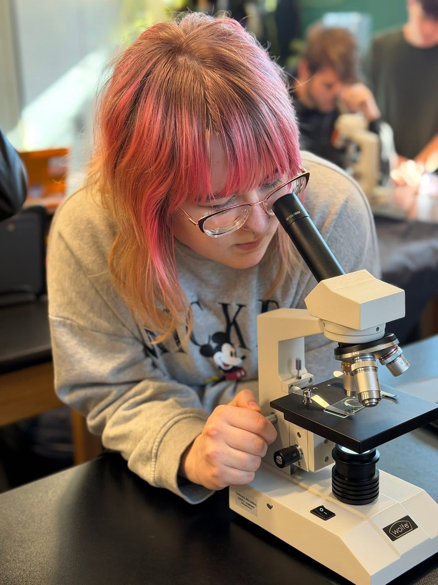A Highland Prep student focusing a microscope in science class
